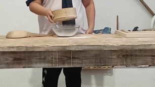 Uczeń przesiewa mąkę przez sito