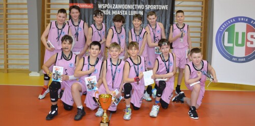 Reprezentacja chłopców w koszykówce pozuje do zdjęcia w sali gimnastycznej