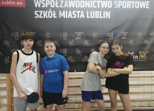 Zawodnicy - dwóch chłopaców i dwie dziewczynki pozują w sali gimnastycznej