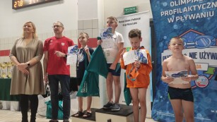 - Dzieci stoją na podium po wręczeniu medali przez p. Otylię Jędrzejczak i p. Mariusza Siembidę