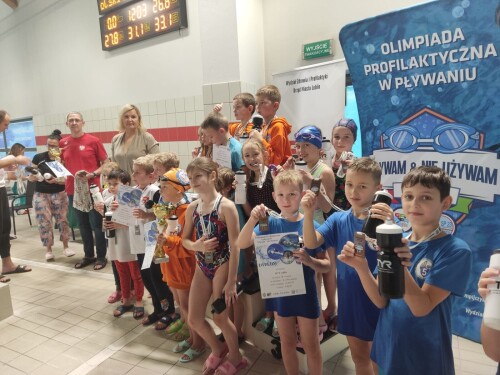 Dzieci stoją na podium po wręczeniu medali przez przez p. Otylię Jędrzejczak i p. Mariusza Siembidę za udział w sztafecie