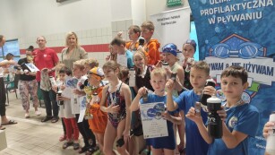 Dzieci stoją na podium po wręczeniu medali przez przez p. Otylię Jędrzejczak i p. Mariusza Siembidę za udział w sztafecie