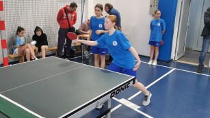 Uczennice grają w tenisa stołowego w sali gimnastycznej
