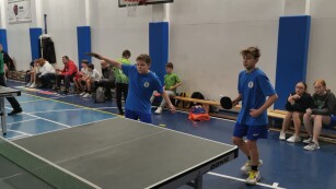 Uczniowie grają w tenisa stołowego w sali gimnastycznej