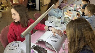 Uczennice klasy 2c na stanowiskach manicure i malują paznokcie – jedne zajmują stanowisko manikiurzystki, drugie klientki.