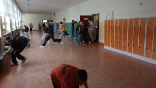 Zdjęcie 2 przedstawia korytarz szkolny po którym biegają uczniowie