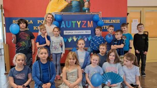 5.	Dzień Świadomości Autyzmu, Uczniowie klasy 1e ubrani na niebiesko, przed tablicą na temat autyzmu.