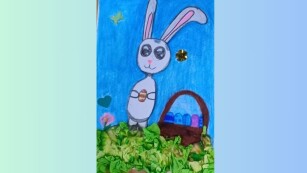 4. Kartka wielkanocna – rysunek – zajączek trzymający pisankę w łapkach oraz koszyk pełen pisanek na trawie z pogniecionej bibuły.