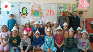 Uczniowie klasy 2 b pozują do zdjęcia w ozdobnych czapkach wykonanych z papieru.